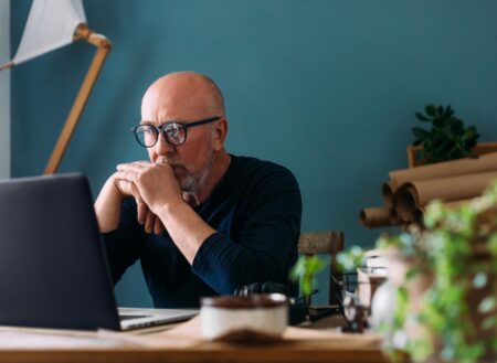 Man in blue jumper looking at his laptop