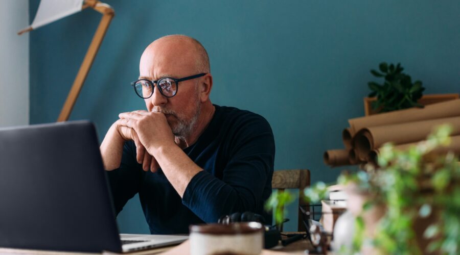 Man in blue jumper looking at his laptop